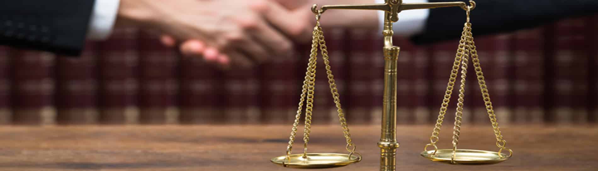 Bilancia della giustizia su una scrivania, davanti a una libreria di codici